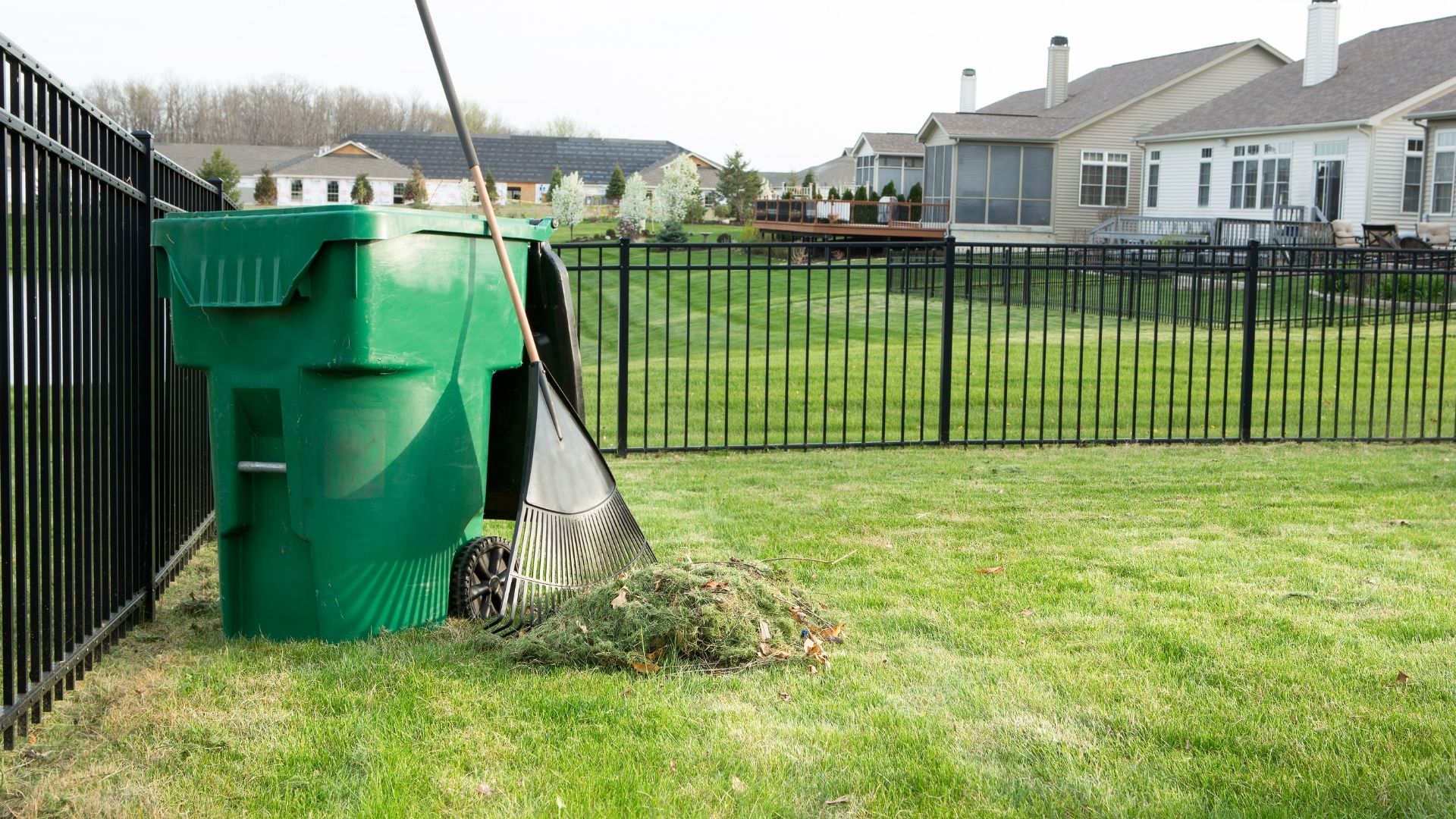 Spring and fall yard cleanup with rake and green waste bin in Houston TX by Leatherwood Lawn Specialists